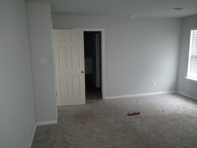 carpeted spare room featuring visible vents and baseboards