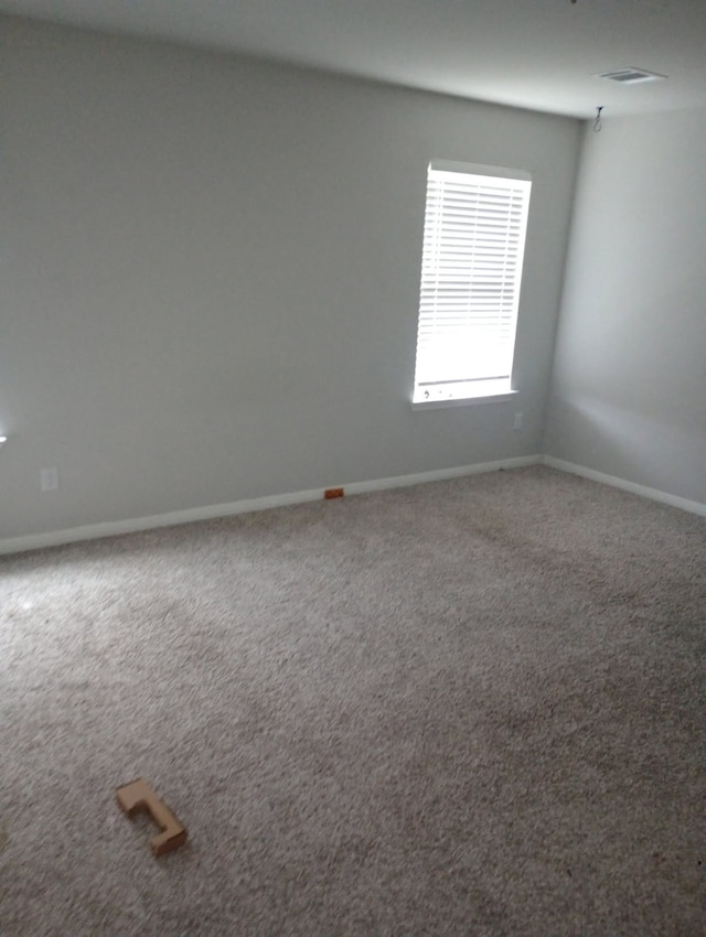 carpeted empty room featuring baseboards