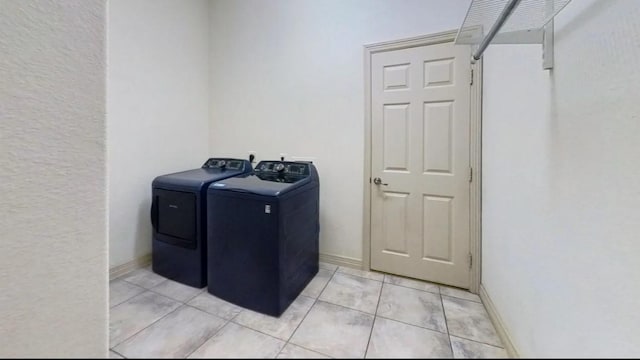 washroom featuring light tile patterned floors, baseboards, washing machine and dryer, and laundry area