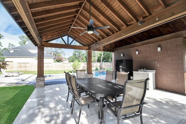 view of patio with a fenced in pool, fence, outdoor dining area, a ceiling fan, and a sink