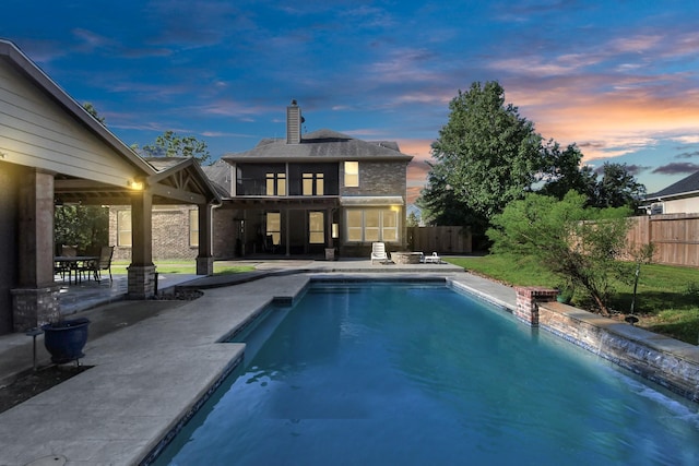 pool at dusk featuring a patio area, a fenced in pool, and a fenced backyard