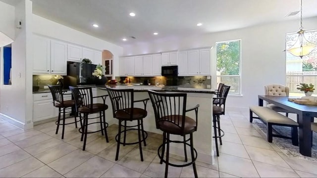 kitchen with black appliances, backsplash, dark countertops, arched walkways, and white cabinets