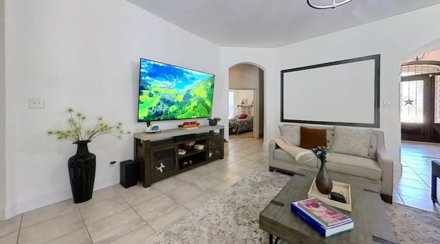 cinema room with arched walkways and light tile patterned flooring