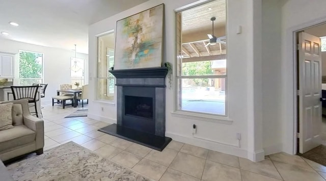 living area with light tile patterned floors, baseboards, a fireplace with raised hearth, and recessed lighting