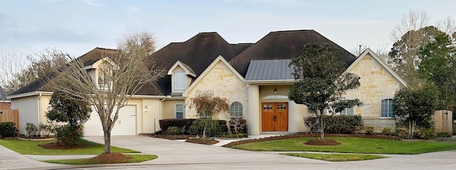 view of front of home with stone siding, driveway, a front lawn, and a garage