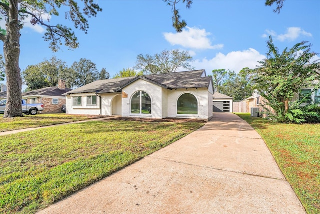 view of front of home with a detached garage, brick siding, central AC, and a front yard