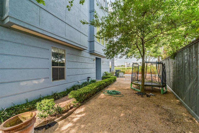 view of yard with a trampoline and fence