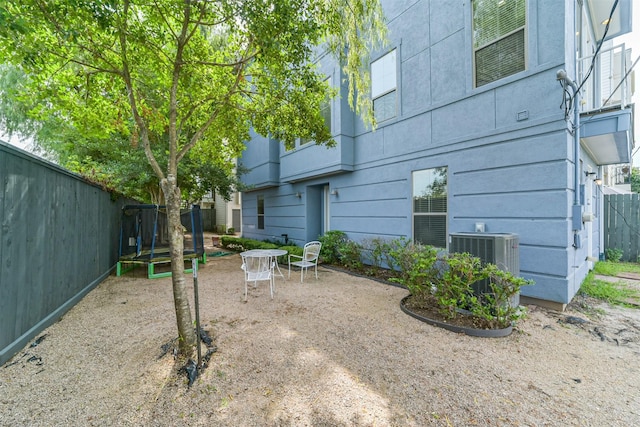 view of yard with a patio, a trampoline, a fenced backyard, and central AC