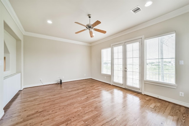 empty room featuring visible vents, wood finished floors, baseboards, and ornamental molding