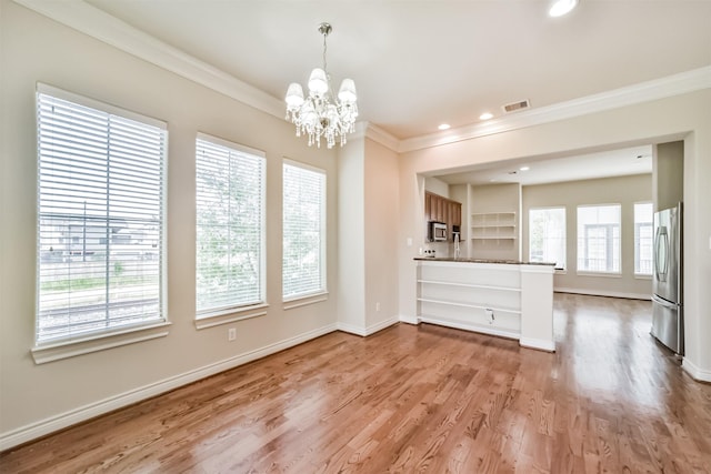 unfurnished dining area with baseboards, visible vents, ornamental molding, light wood-style floors, and a chandelier