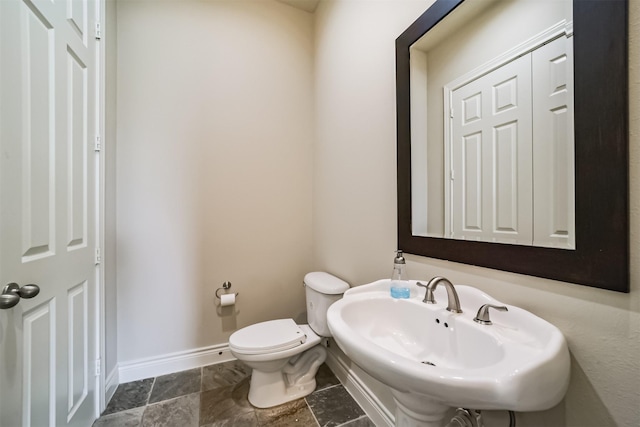 bathroom featuring toilet, baseboards, and a sink