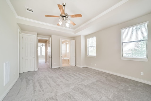 unfurnished bedroom featuring a tray ceiling, multiple windows, and visible vents