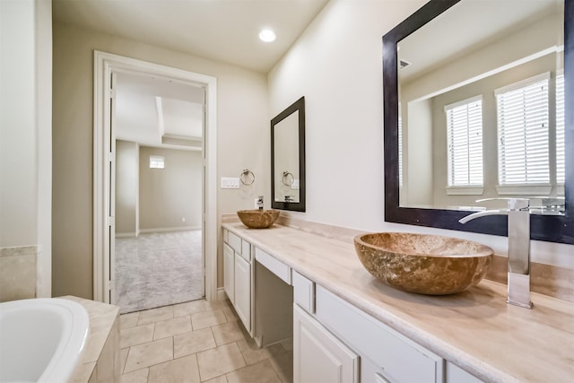 full bath with tile patterned flooring, double vanity, a relaxing tiled tub, and a sink