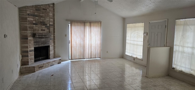 unfurnished living room featuring tile patterned flooring, vaulted ceiling, a fireplace, and a textured ceiling