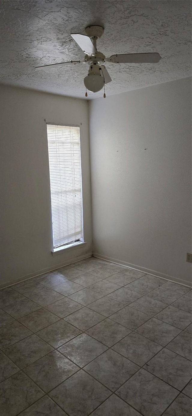 unfurnished room featuring a ceiling fan, baseboards, and a textured ceiling