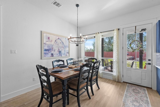 dining room with a notable chandelier, baseboards, visible vents, and light wood finished floors