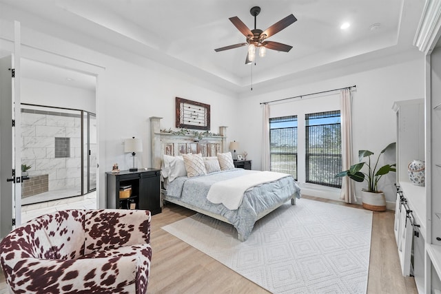 bedroom with a raised ceiling, light wood-type flooring, and ceiling fan