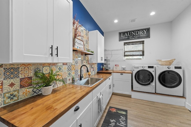 kitchen featuring butcher block countertops, a sink, backsplash, white cabinetry, and washing machine and clothes dryer