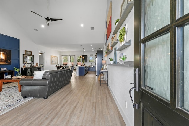 living area with visible vents, high vaulted ceiling, and light wood finished floors