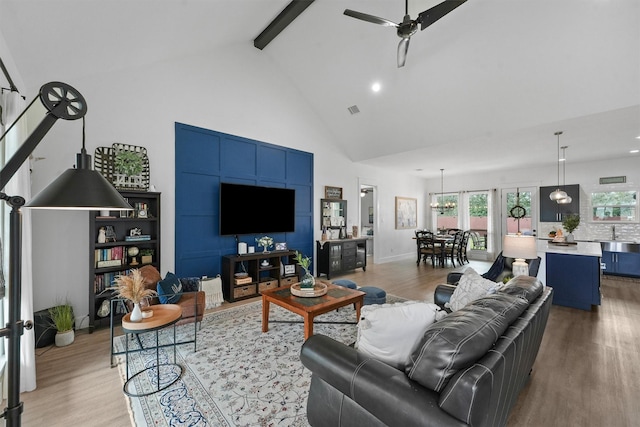 living room with beam ceiling, light wood finished floors, and high vaulted ceiling