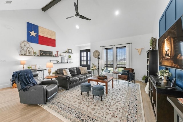 living area featuring beamed ceiling, high vaulted ceiling, a ceiling fan, wood finished floors, and baseboards