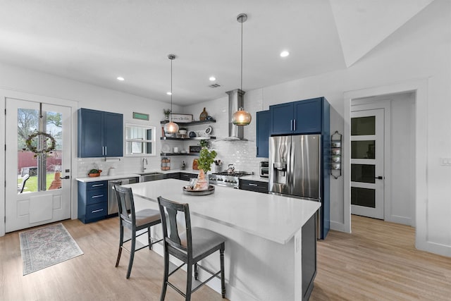 kitchen with open shelves, wall chimney exhaust hood, blue cabinets, and appliances with stainless steel finishes