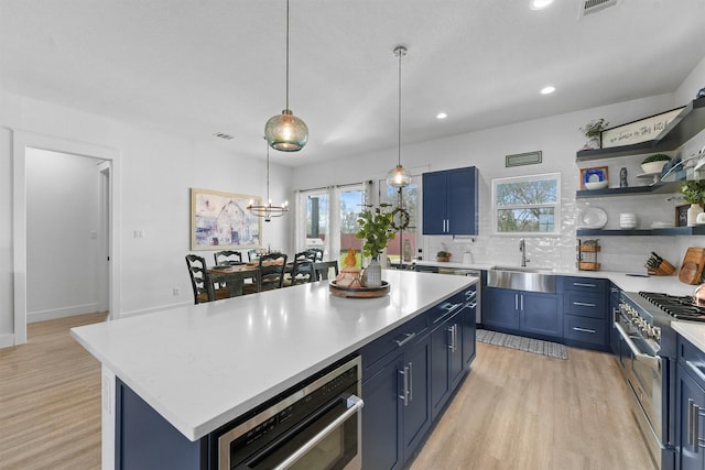 kitchen featuring blue cabinetry, a sink, light countertops, and stainless steel range