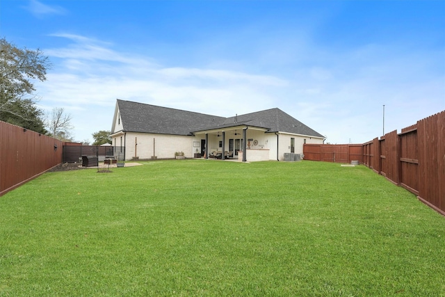 back of property with a fenced backyard, a patio area, a shingled roof, and a yard