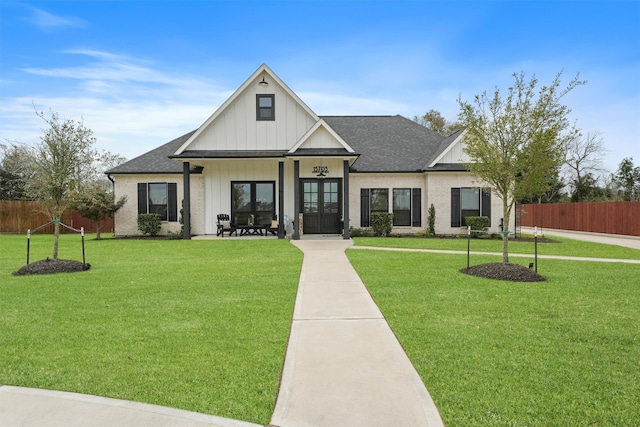 modern farmhouse style home featuring board and batten siding, a front lawn, and fence