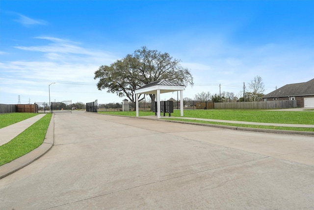 view of street featuring curbs, a gate, a gated entry, sidewalks, and street lighting