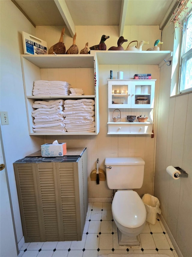 bathroom with tile patterned floors, beam ceiling, and toilet