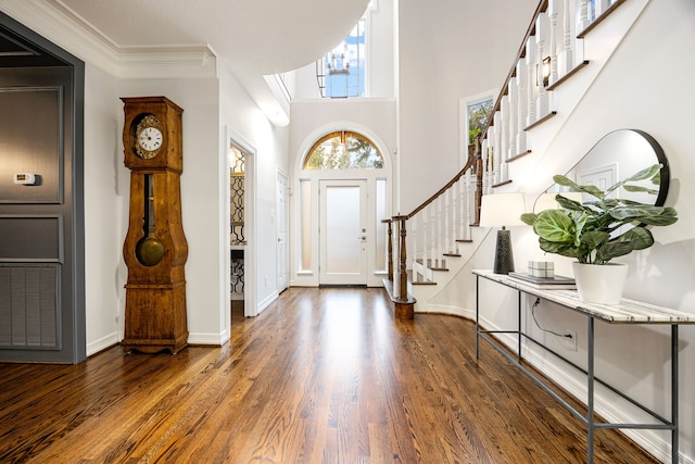 entrance foyer with stairway, crown molding, baseboards, and wood finished floors