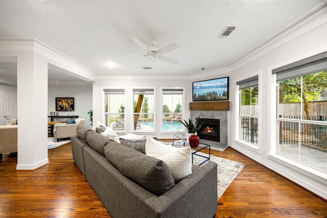 living room featuring wood finished floors, crown molding, a fireplace, and visible vents