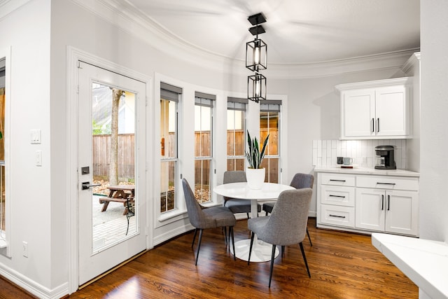 dining space with dark wood finished floors, crown molding, and baseboards