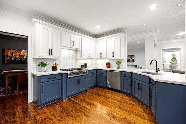 kitchen with blue cabinetry, a peninsula, white cabinets, stainless steel appliances, and a sink