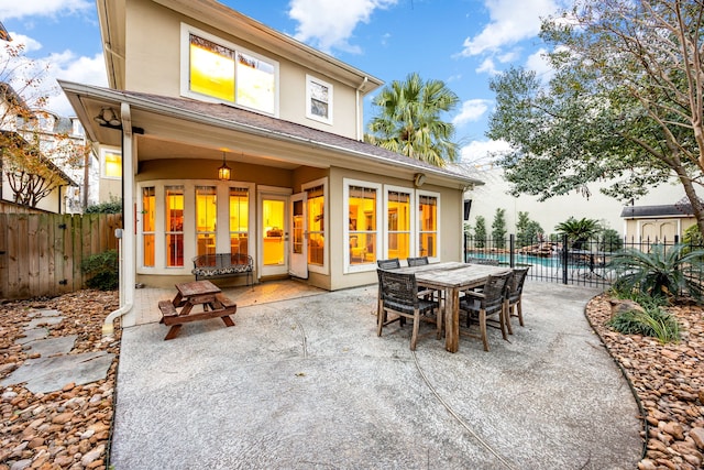 rear view of property featuring a patio area, stucco siding, and fence