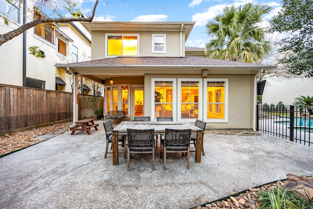 rear view of house with a patio, outdoor dining area, fence, and stucco siding