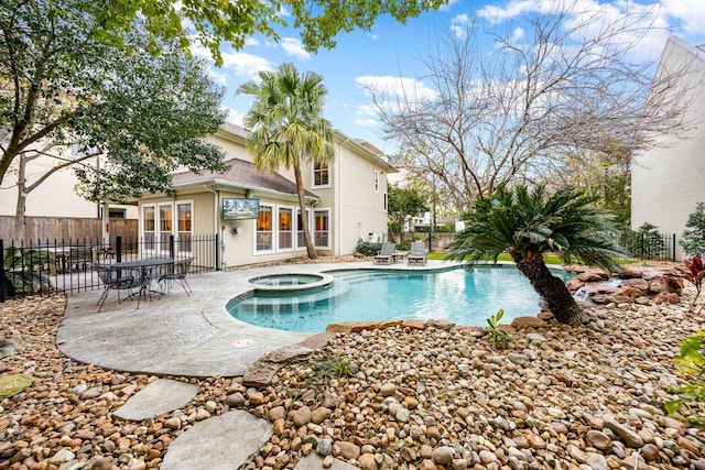 view of swimming pool featuring an in ground hot tub, fence, and a patio