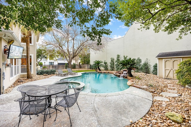 view of pool with a pool with connected hot tub, a storage shed, a fenced backyard, a patio area, and an outbuilding