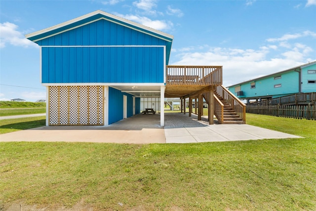 back of property featuring a carport, stairway, a yard, and a wooden deck