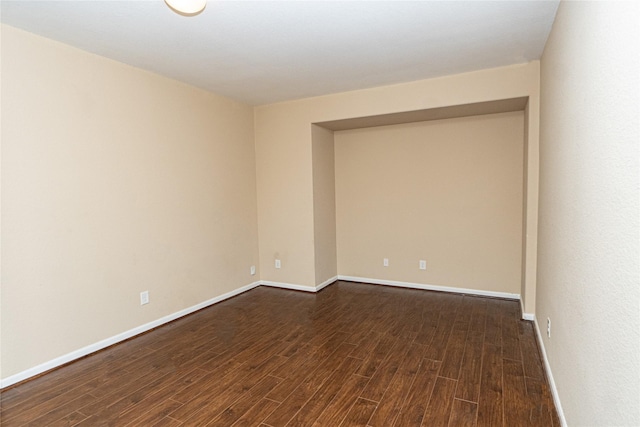 empty room featuring baseboards and dark wood-style flooring