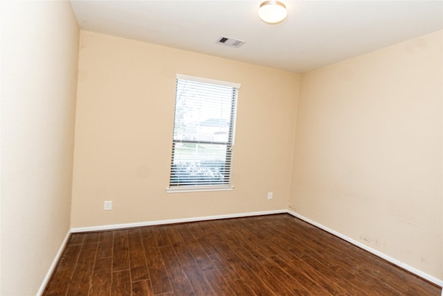 unfurnished room with visible vents, baseboards, and dark wood-style flooring