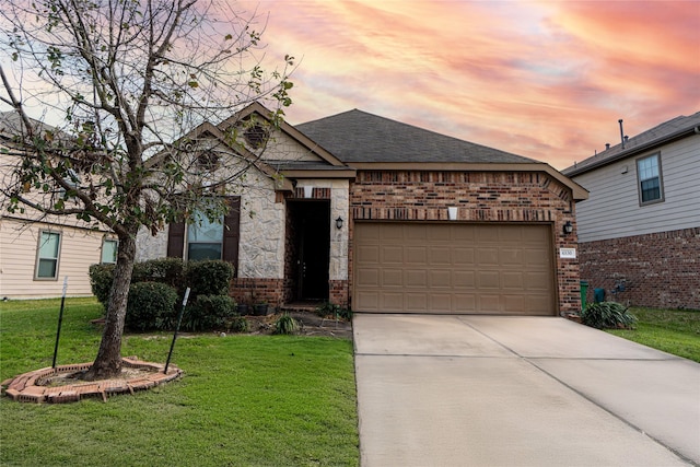 view of front of property featuring driveway, a yard, a shingled roof, a garage, and brick siding