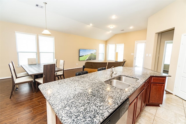 kitchen with vaulted ceiling, an island with sink, a healthy amount of sunlight, and a sink