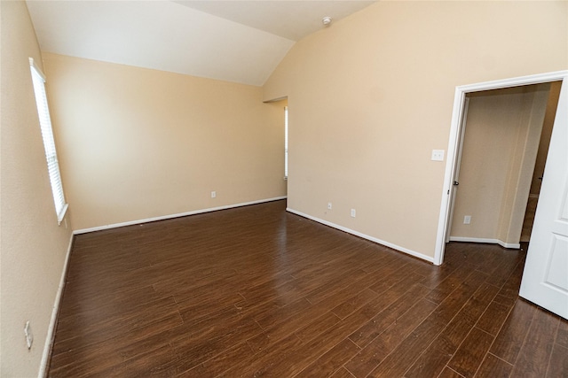 empty room featuring baseboards, dark wood-style floors, and vaulted ceiling