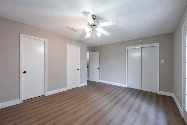 unfurnished bedroom featuring a ceiling fan, wood finished floors, baseboards, and a textured ceiling