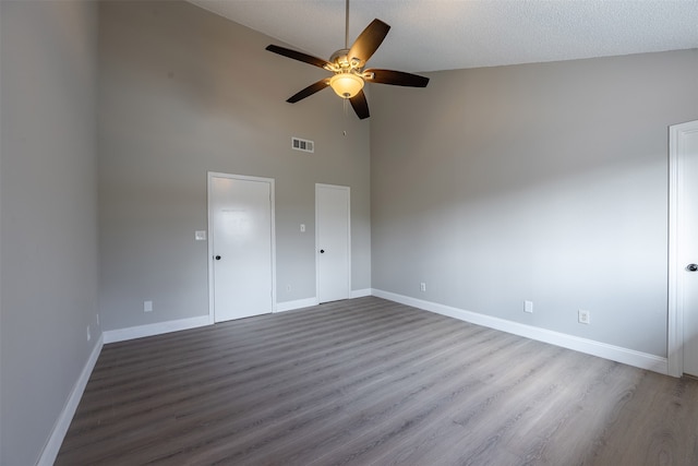 empty room featuring a ceiling fan, wood finished floors, visible vents, and baseboards