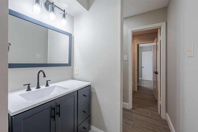 bathroom featuring vanity, baseboards, and wood finish floors