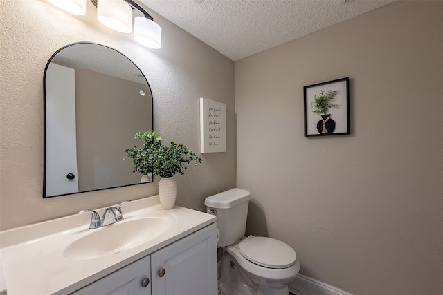 half bath featuring a textured ceiling, toilet, vanity, and a textured wall