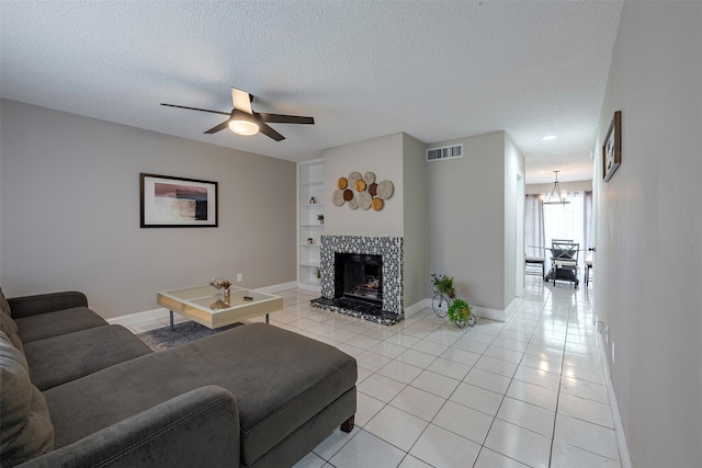 living room with light tile patterned floors, visible vents, a textured ceiling, and built in features